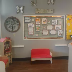 A cozy and inviting lobby, complete with comfortable seating and a colorful bulletin board showcasing heartwarming moments from our daycare. It’s the perfect space for families to feel welcomed and connected.