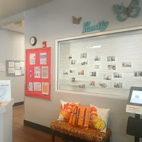 A cozy and inviting lobby, complete with comfortable seating and a colorful bulletin board showcasing heartwarming moments from our daycare. It’s the perfect space for families to feel welcomed and connected.