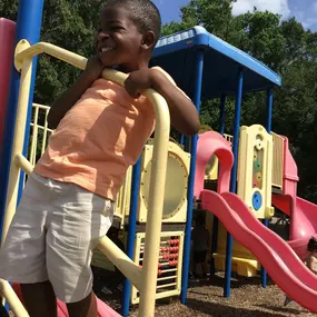 A joyful moment captured as a child smiles while enjoying playtime on the playground.
