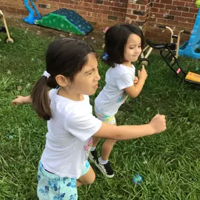 Children dancing and laughing as they play with bubbles, adding an extra touch of joy to their outdoor activity.