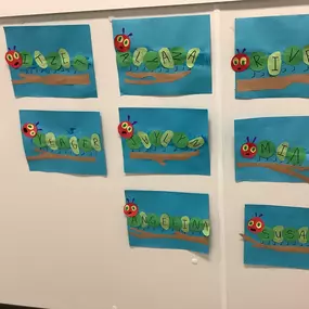 A display of caterpillar-themed crafts made by children using pom-poms, pipe cleaners, and construction paper.