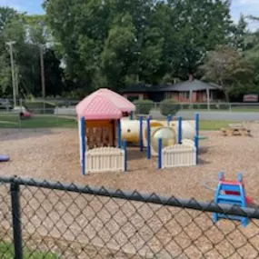A calm and inviting playground with swings, slides, and a playhouse, perfect for imaginative outdoor play.