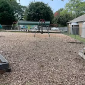 An inviting swing set in a quiet corner of the playground, ready for children to enjoy the freedom of soaring through the air.