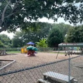 A calm and inviting playground with swings, slides, and a playhouse, perfect for imaginative outdoor play.