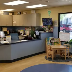 A cozy and inviting lobby, complete with comfortable seating and a colorful bulletin board showcasing heartwarming moments from our daycare. It’s the perfect space for families to feel welcomed and connected.