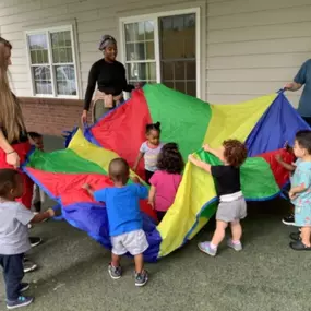 Colorful teamwork in motion — parachute play builds coordination, cooperation, and lots of laughter!