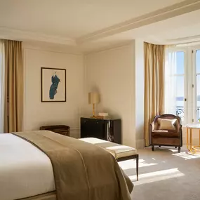 Spacious bedroom with king bed, French windows, and soft beige decor at The Woodward Geneva.