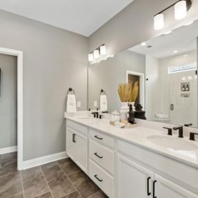 Lavish primary bathrooms with dual sink vanities, walk-in showers, private water closets, and huge walk-in closets