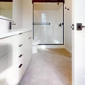 Gorgeous bathroom with marble-look flooring, built-in vanity area with two sinks, and glass-enclosed shower all complete with matte black hardware