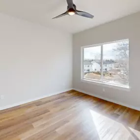 Modern bedroom with plank flooring, large sliding window, and ceiling fan