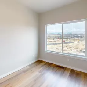 Expansive bedroom with plank flooring and a large window