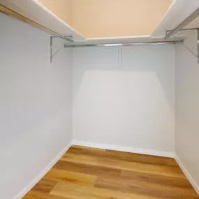 Walk-in closet with plank flooring and built-in storage with silver hanging racks