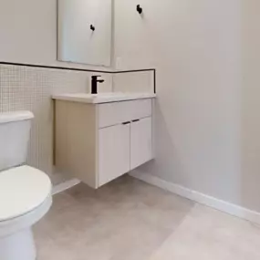 Chic bathroom with marble-look flooring, cabinetry with matte black fixtures, and minimalist tile on the wall