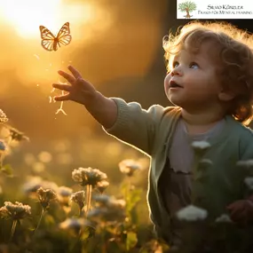 Kind berührt Schmetterling in Abendsonne