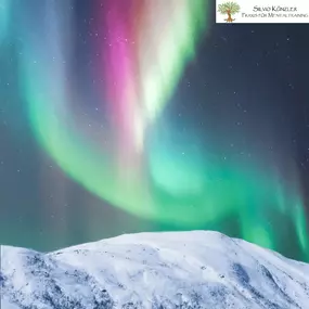 Polarlichter über verschneitem Berg