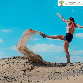 Sportlerin im Sand unter blauem Himmel