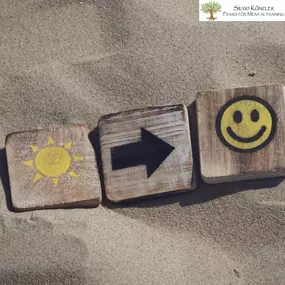 Smiley im Sand mit Sonne