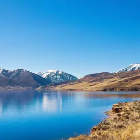 Mt. Timpanogos reflects in the water of Deer Creek Reservoir near new construction in Heber City, UT