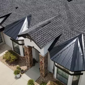 Close-up aerial view of a recently completed residential roofing project by Armor Roofing FL, featuring a combination of architectural shingles and sleek black metal roof accents. Ideal example of high-quality craftsmanship by a roofer near me in Florida.