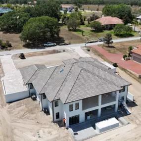 Aerial view of a recently completed tile roof installation by Armor Roofing FL on a large custom home, showcasing expert craftsmanship and quality materials in a residential project.