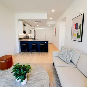 The living area at The Gio showcases an open-concept layout leading into the modern kitchen and bar area.