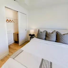 A bright, minimalist bedroom at The Gio showcases a queen-sized bed with crisp white bedding.