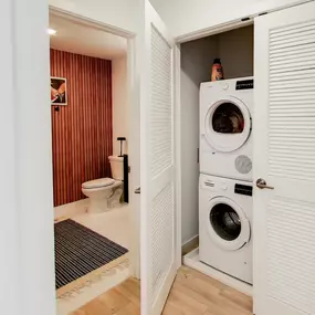 The dedicated laundry closet and a view into a unique bathroom are presented at The Gio.