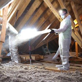 A photograph captures the interior of an attic space, showcasing newly installed insulation lining the walls and ceiling. The insulation material, likely fiberglass or cellulose, fills the space evenly, providing a barrier against heat loss in winter and heat gain in summer. The clean and well-installed insulation suggests energy efficiency and improved comfort within the home, highlighting the importance of proper insulation for maintaining temperature control and reducing energy costs