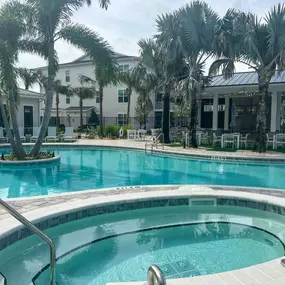 A large swimming pool with a hot tub in front of a building