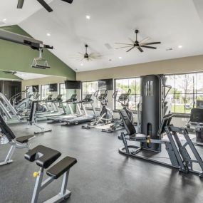 A spacious fitness center with cardio equipment and windows