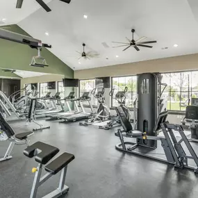 A spacious fitness center with cardio equipment and windows