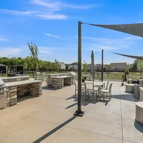 An outdoor patio with a grill and tables and chairs