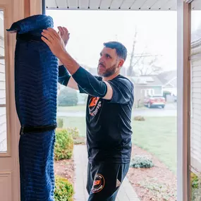 A CT Moving and Storage crew member secures a padded moving blanket around a door frame to protect it during the moving process.