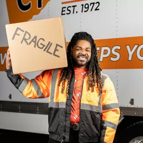 A CT Moving and Storage team member proudly holds a box labeled 