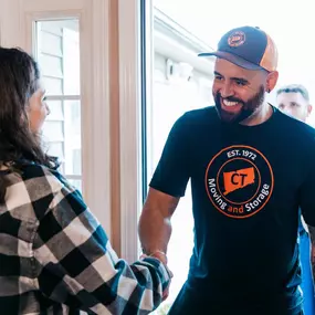 A smiling team member greets a customer with a handshake at the start of the move.