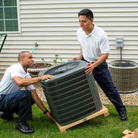 Two HVAC Technicians Moving a New Air Conditioner
