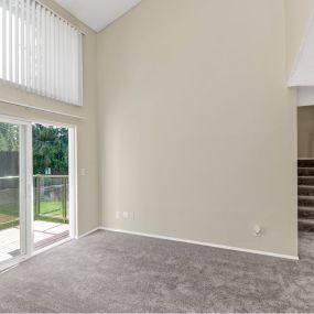 Living room with windows and a slider door and stairs to the second floor