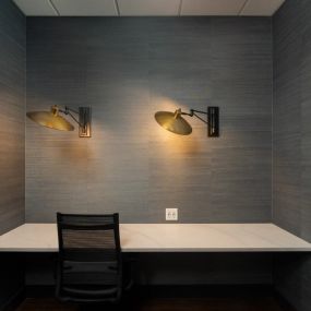 Private resident workspace with built-in desk, two gold wall sconces, and outlets