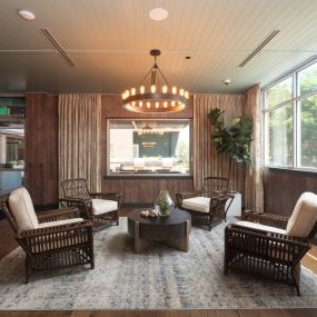 Stunning community lounge with wicker chairs, modern chandelier, and large windows