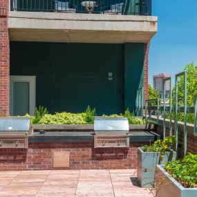 Red brick patio lounge with plants and two BBQ grills