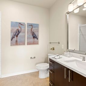 View into the bathrom with a glass enclosed shower and well-lit vanity area with a large mirror