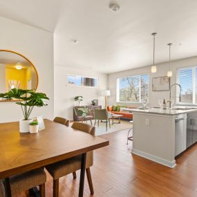 a modern dining room with a wooden table and chairs with a view into the stunning kitchen and luxurious living area