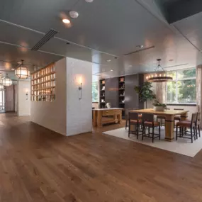 View of the resident lounge with white brick walls, square wooden table with cognac colored chairs and wooden floors