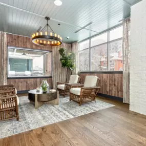 Resident common area with wooden furniture, modern style chandelier, and large windows