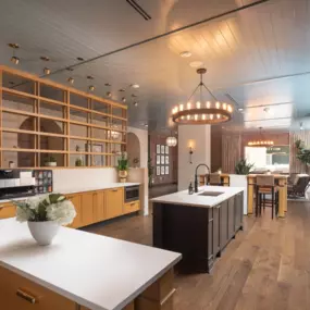 View into the luxurious resident demo kitchen and lounge spaces and dining area of a modern home with wood floors and white countertops