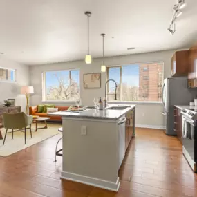 Spacious kitchen with hardwood flooring and an island with view into well-decorated living room