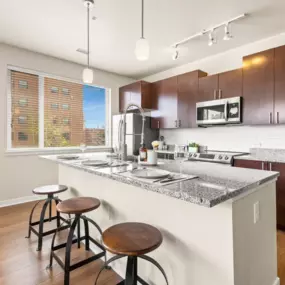 View of the kitchen with a granite island with barstool seating and pendant lighting