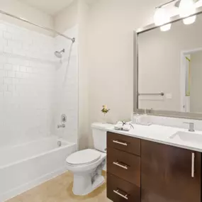 Spacious bathroom with tiled shower, bathtub, and updated vanity area with above-mirror lighting