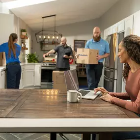 Moving crew packing home with family at table