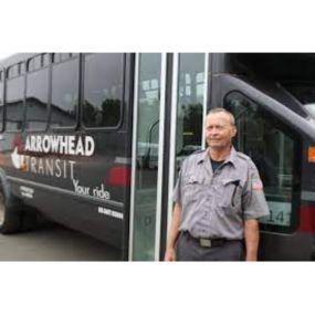 Driver in front of arrowhead transit bus